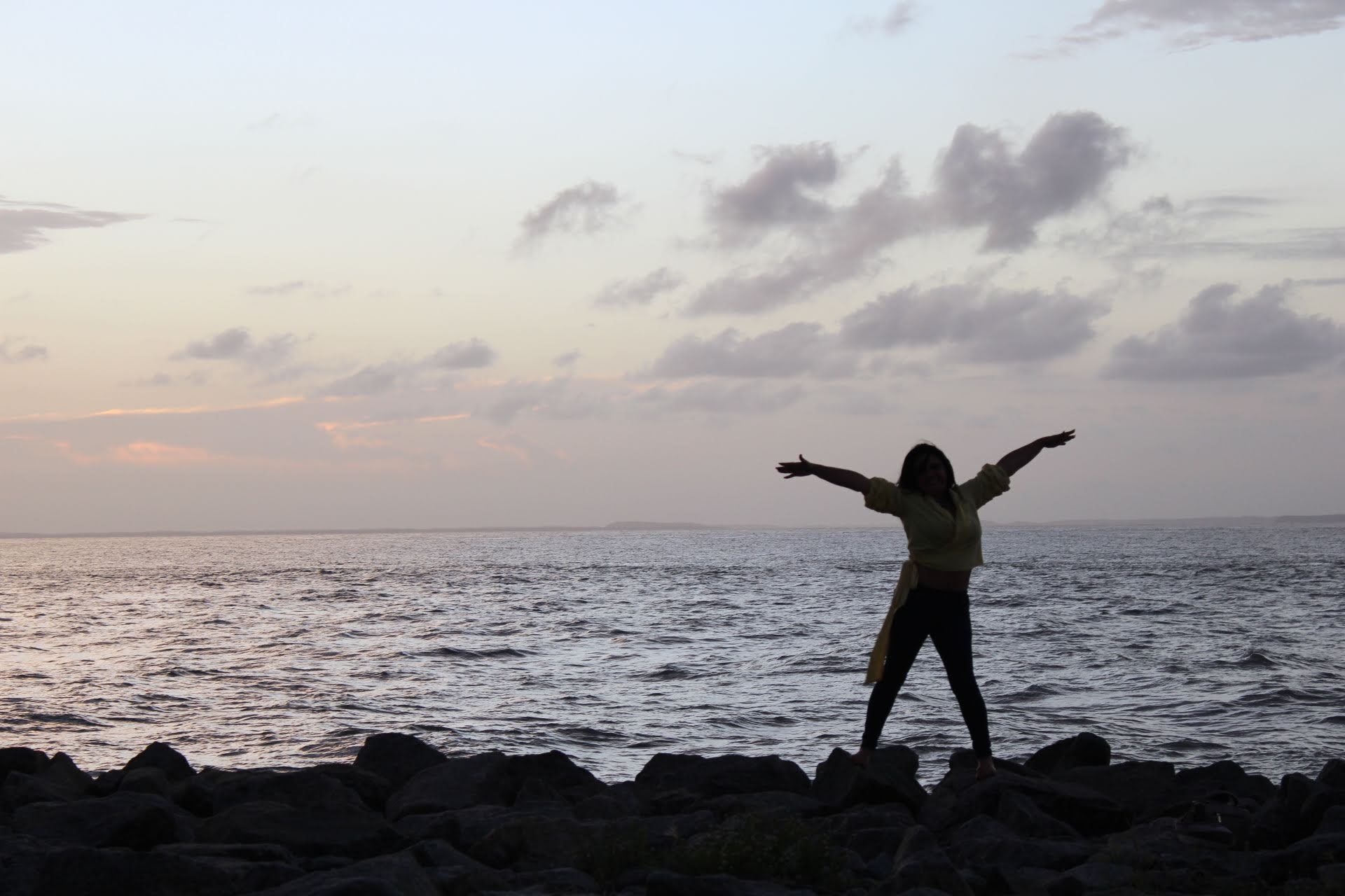 Ana Maria no pôr do sol com os braços abertos